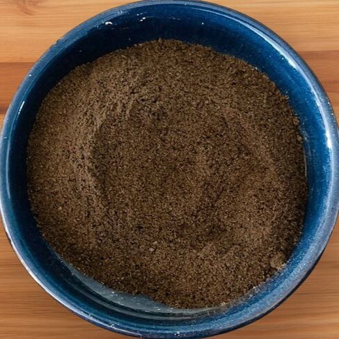 Poudre de chébé pure brun-vert dans un bol rond, en gros plan